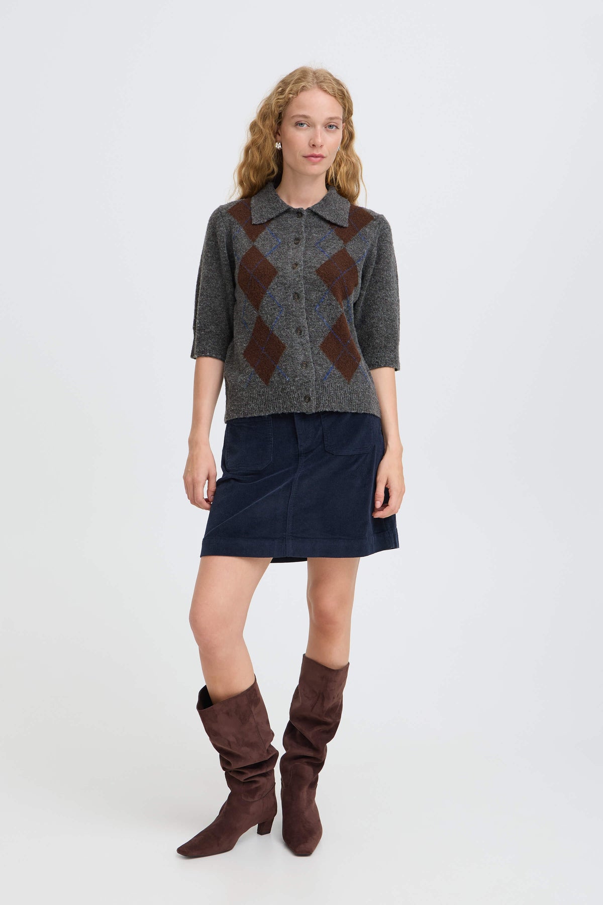 Model wearing the b.young Ofira argyle cardigan with a navy skirt and brown boots