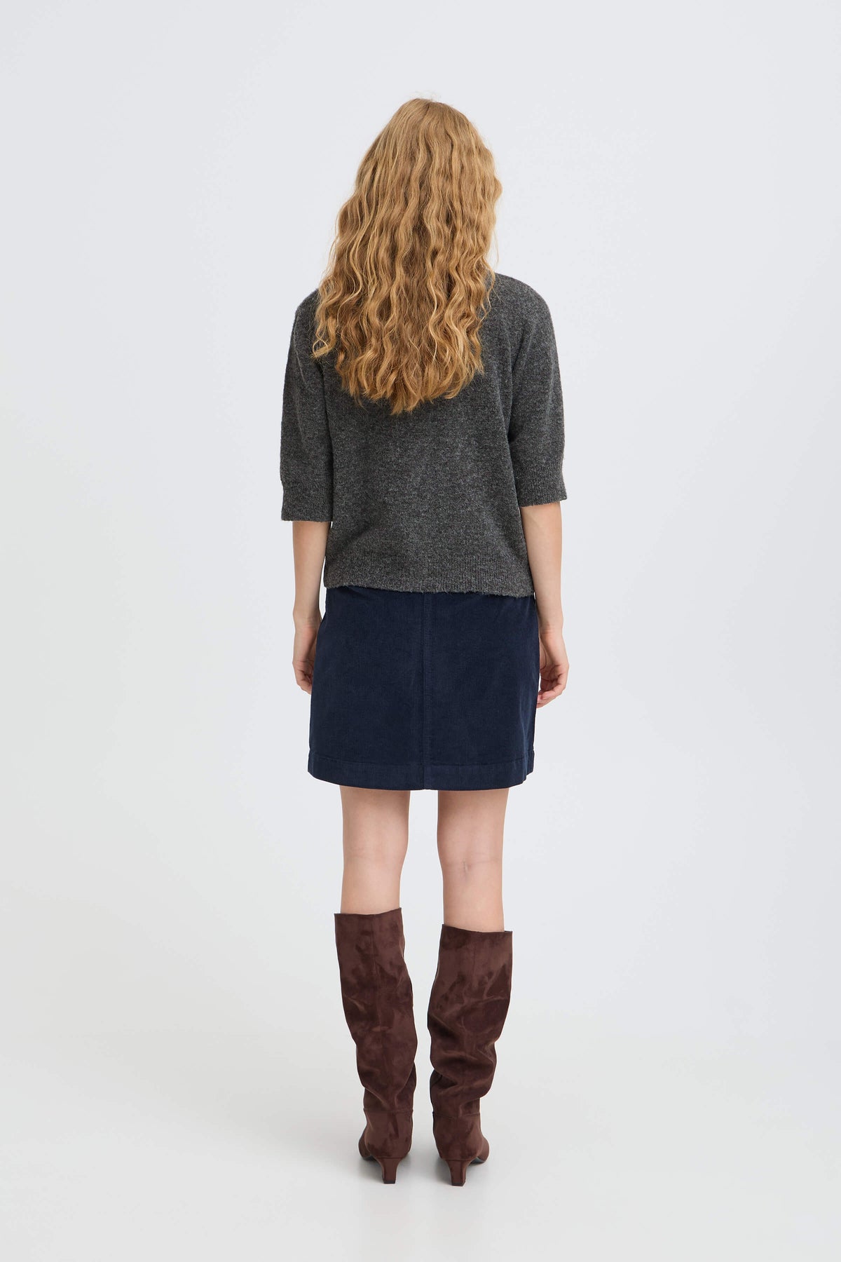 Back view of model wearing the b.young Ofira cardigan with a navy skirt and brown boots