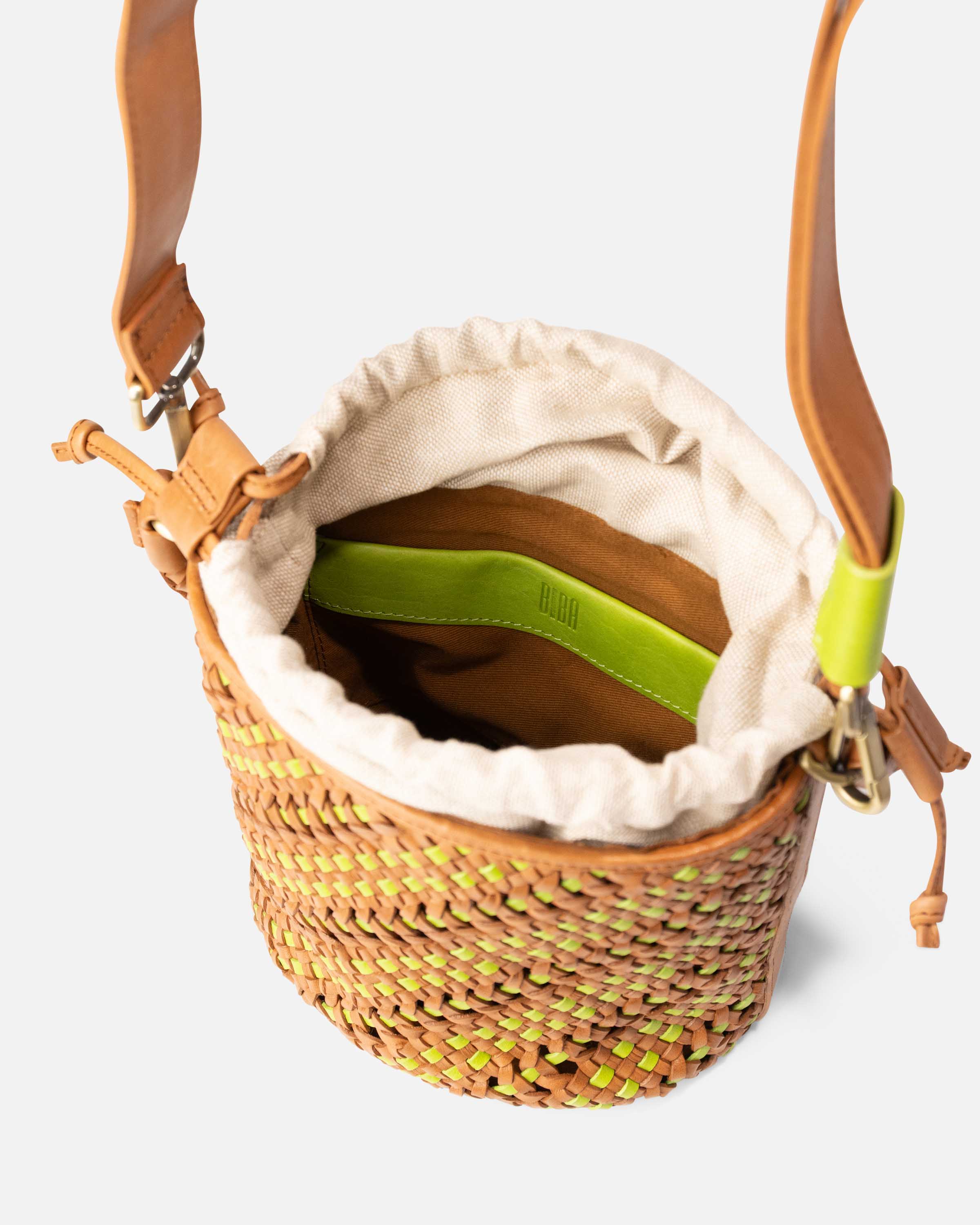 A woven straw bucket bag with tan leather straps, a cream fabric lining, and a bright lime green interior accent from BIBA