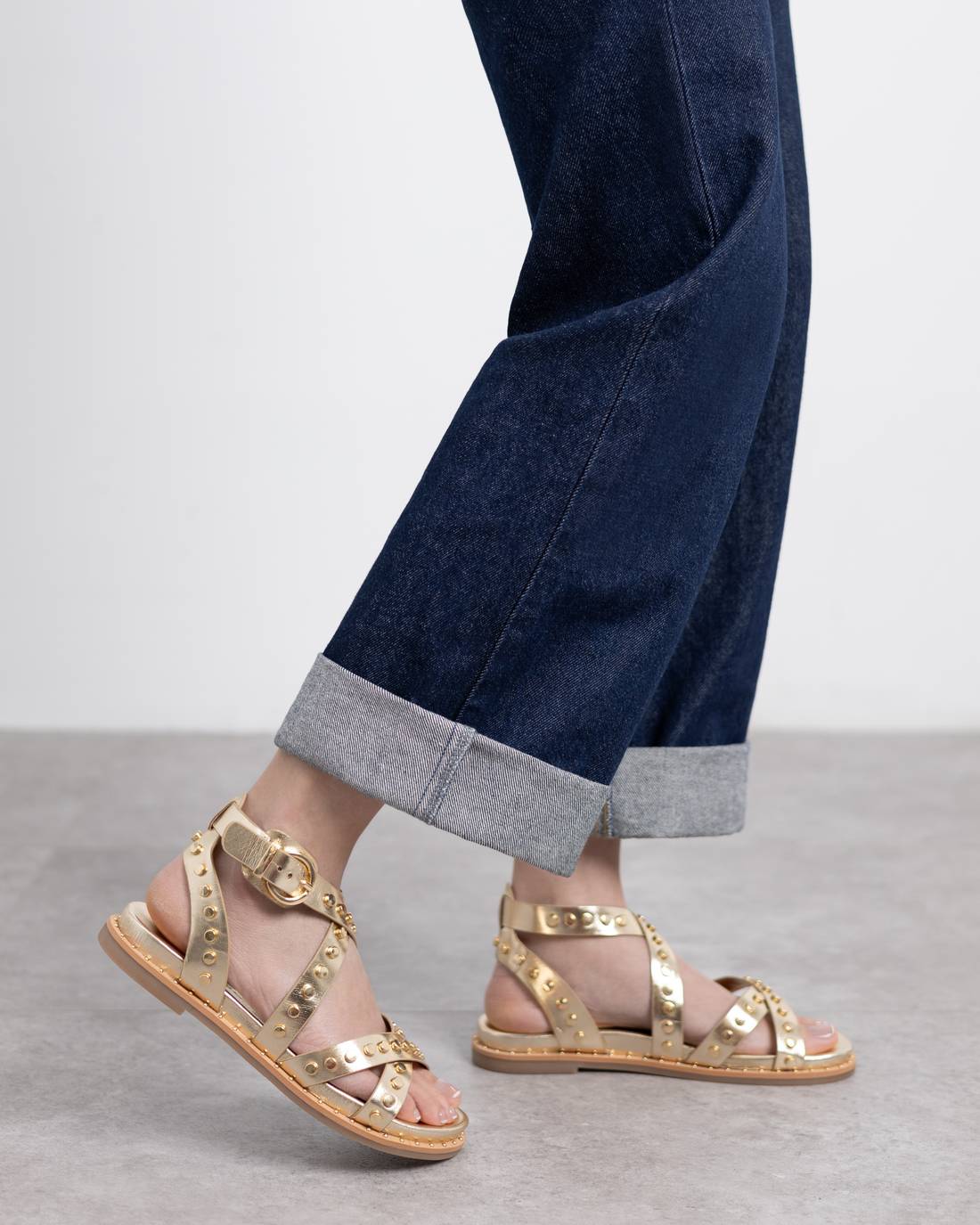 Woman weaking gold studded sandals with criss-cross straps