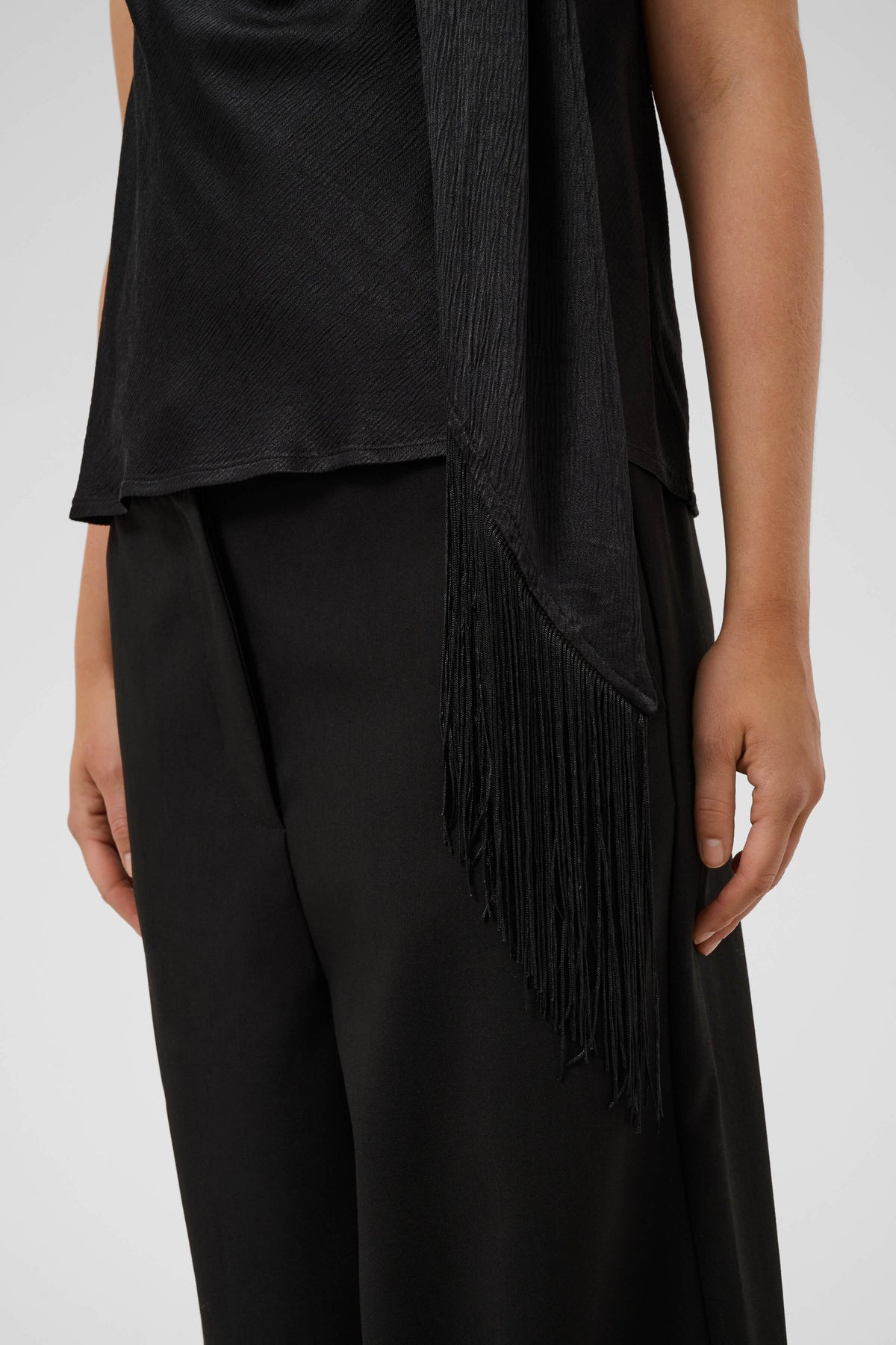 Close-up of the Mirabella Aragat Top with a draped cowl neckline and fringe