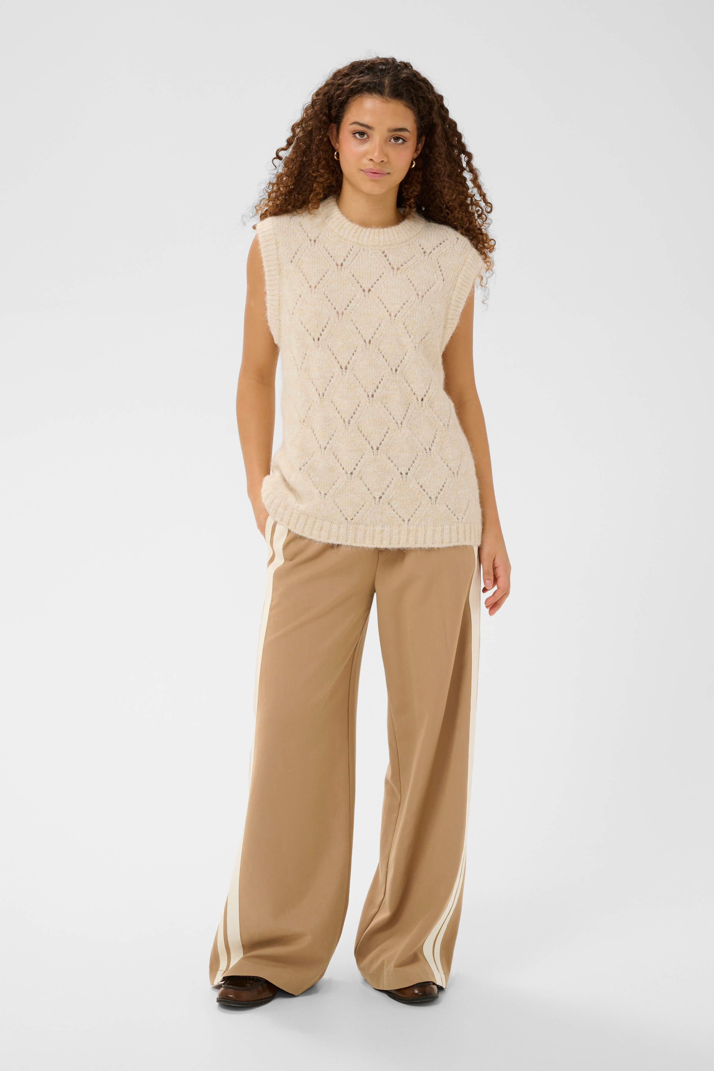An outfit with full-length camel trousers with cream stripes