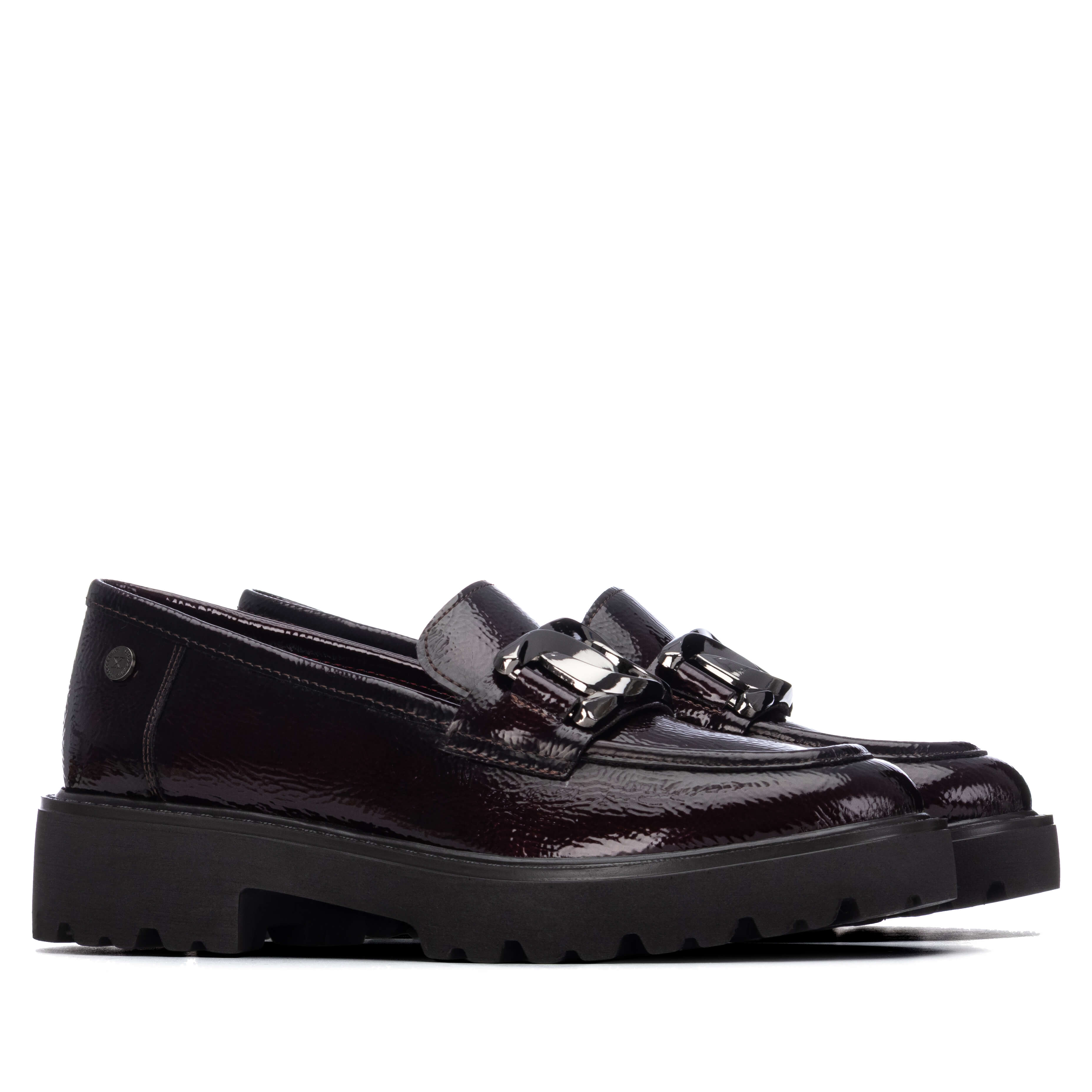 A pair of dark burgundy patent leather loafers with chunky black platform soles and silver-tone buckle details from Xti